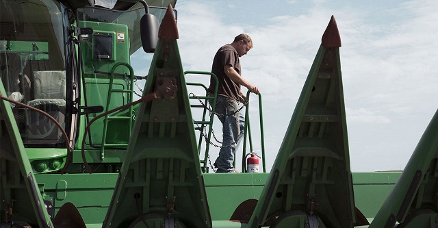 Man stepping out of a combine purchased with an equipment loan from Farm Credit Mid-America.