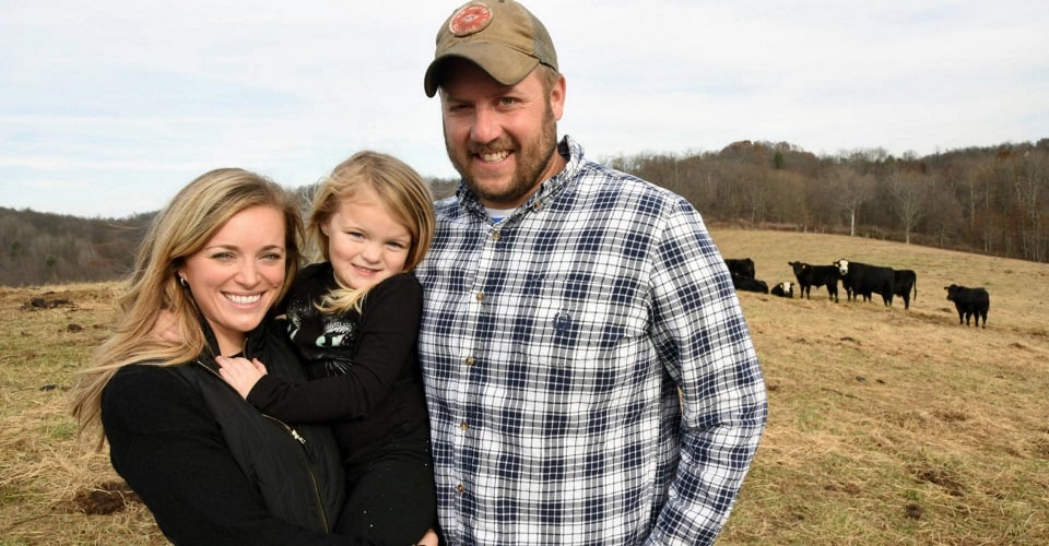 Family standing in cattle field purchased with small agricultural loans from Farm Credit Mid-America.