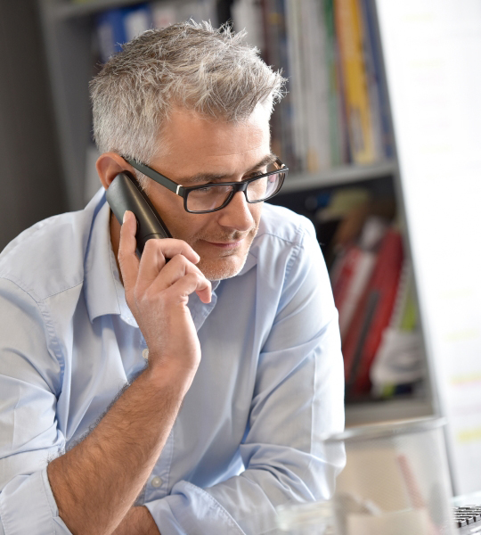 Man talks on a phone at a desk about capital markets financing.