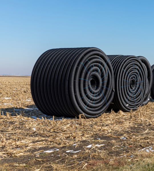 Rolls of tiling in empty field.