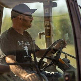 Man driving tractor who receives patronage from Farm Credit Mid-America.