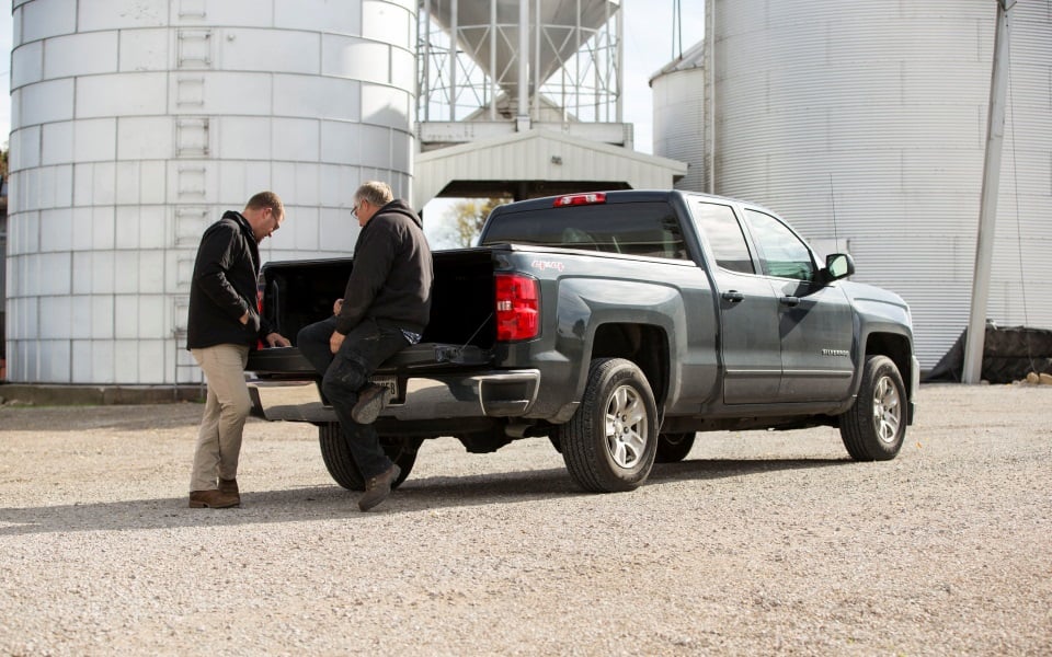 Two men talk on truck tailgate.