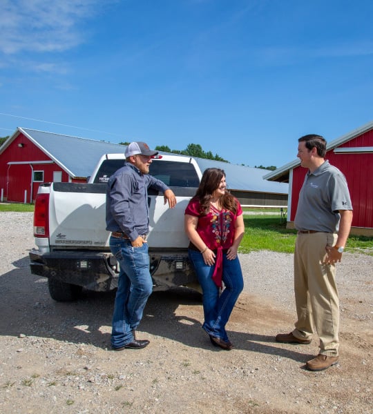 Three people stand around a truck.