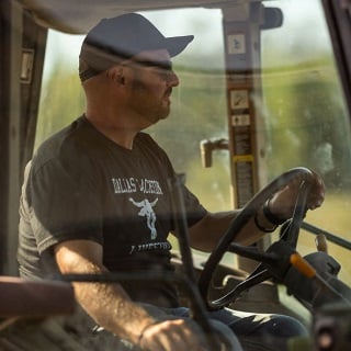 Man driving tractor who receives patronage from Farm Credit Mid-America.